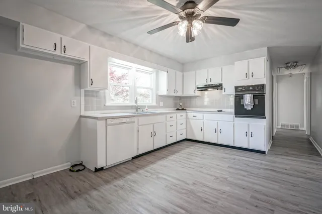 a kitchen with granite countertop white cabinets and white stainless steel appliances