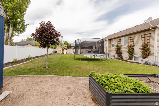 972 West 2840th Street South Logan, UT 84321 - Photo 43 of 46 Spacious backyard featuring a manicured lawn, a mature red-leaf tree, and a white privacy fence