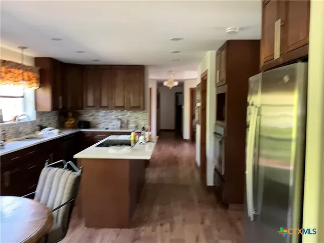 a kitchen with kitchen island a counter top space a sink a refrigerator and a window