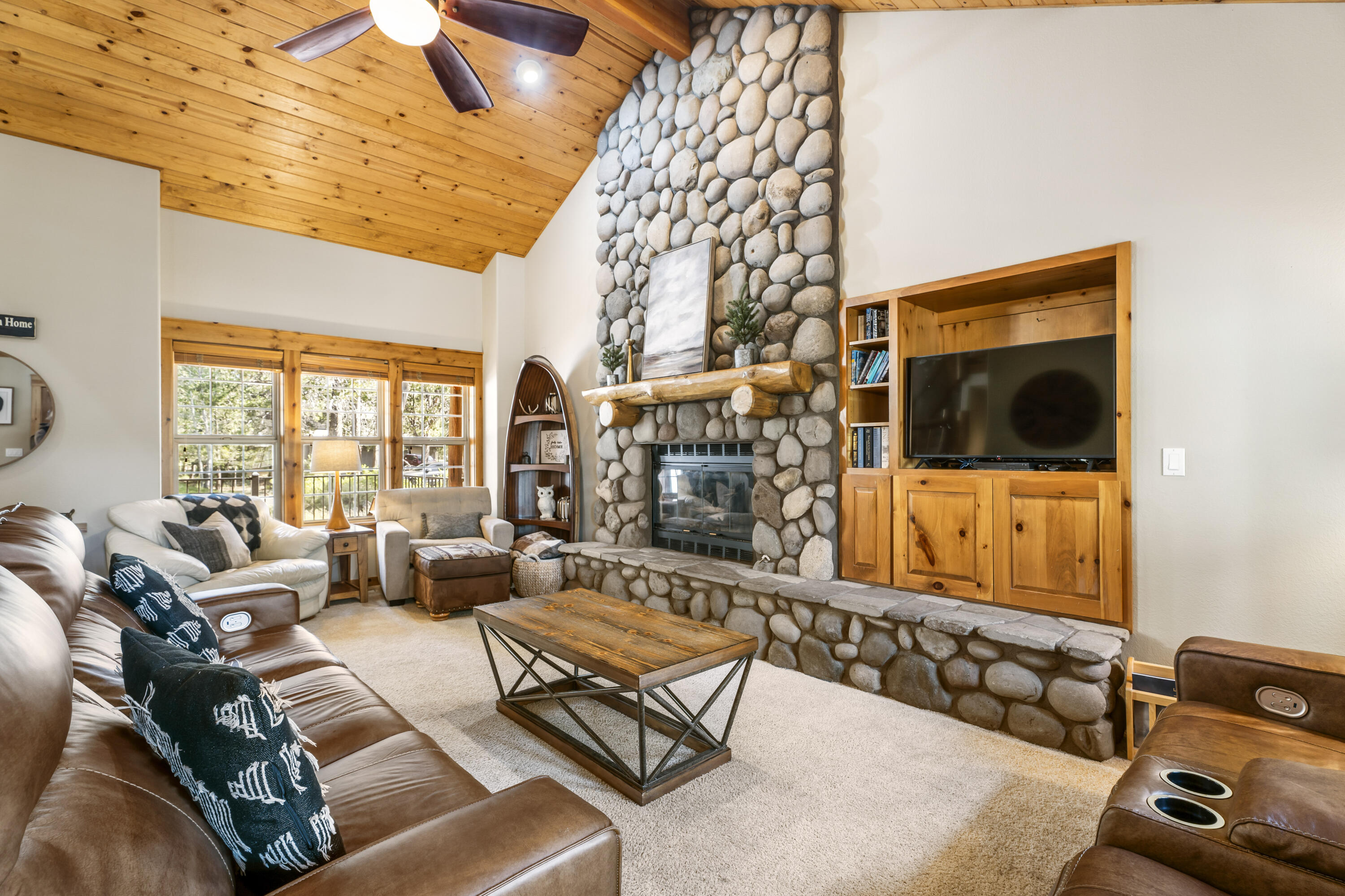 18189 Oregon Loop, Unit 5 Sunriver, OR 97707 - Photo 2 of 41 This cozy living room features a stunning floor-to-ceiling river rock fireplace, warm wood accents, and comfortable seating that creates a perfect mountain retreat ambiance.