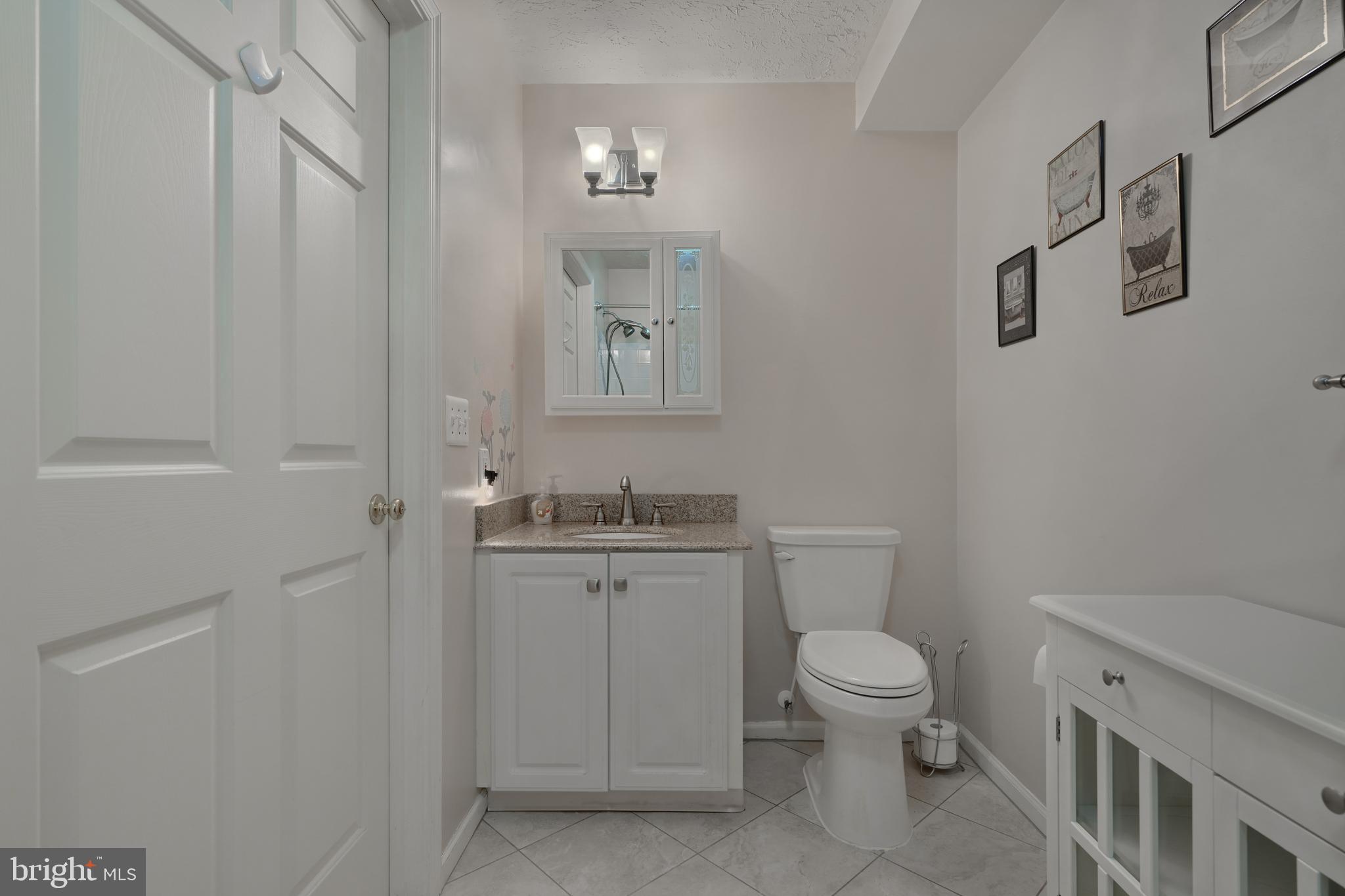 5318 Millfield Road, Unit 5318 Rosedale, MD 21237 - Photo 13 of 26 a bathroom with a granite countertop toilet a sink a mirror and a shower
