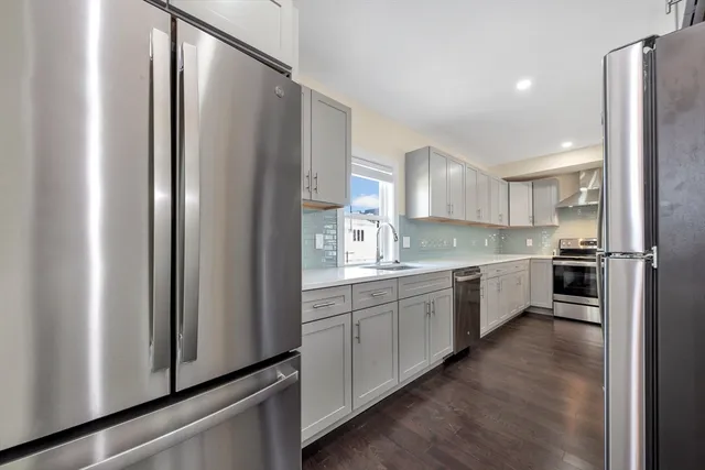 a large kitchen with a refrigerator a sink and white cabinets