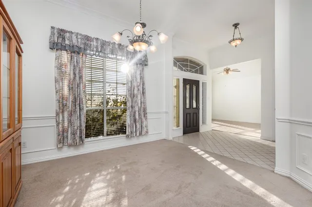 a view of a big room with a chandelier fan and kitchen view