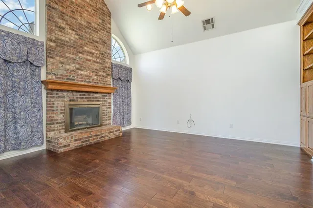 an empty room with a fireplace and wooden floor