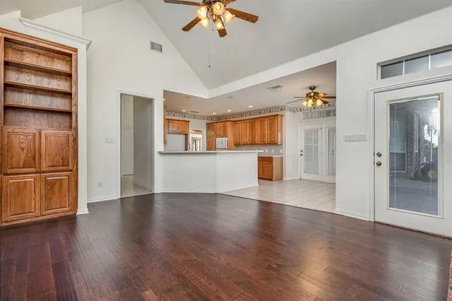 an empty room with wooden floor chandelier and windows