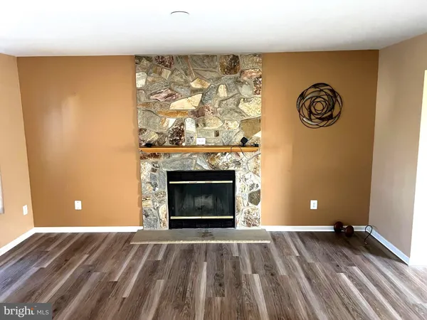 a view of empty room with wooden floor and a fireplace