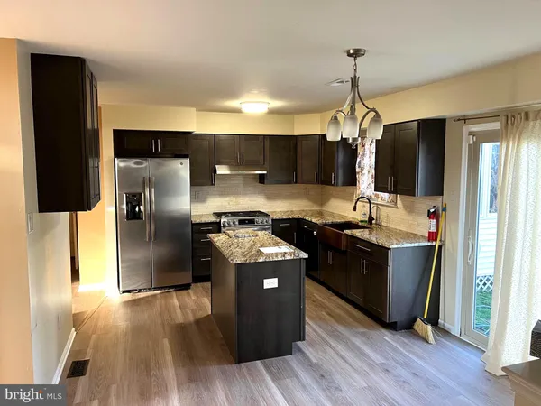 a kitchen with stainless steel appliances granite countertop a refrigerator a stove and a wooden floors