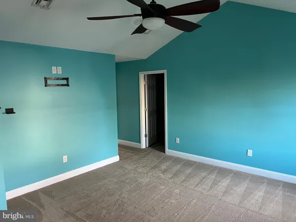 an empty room with a fan & a window