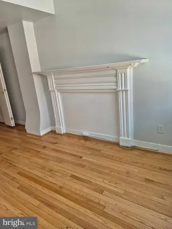 a view of an empty room with wooden floor and closet