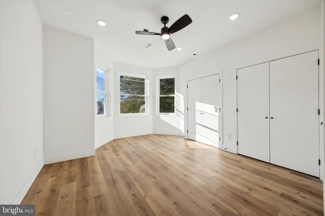 a view of empty room with wooden floor and ceiling fan