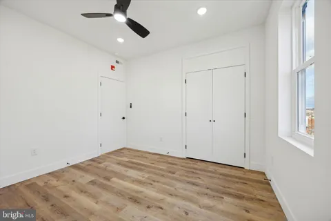 an empty room with a ceiling fan and window