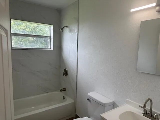 a white toilet sitting next to a bath tub