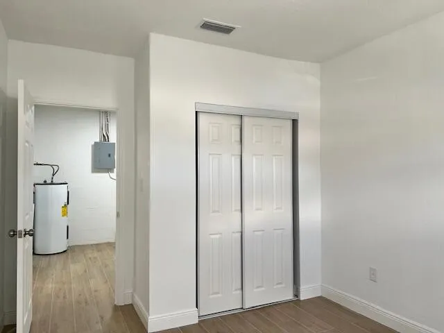an empty room with wooden floor and mirror