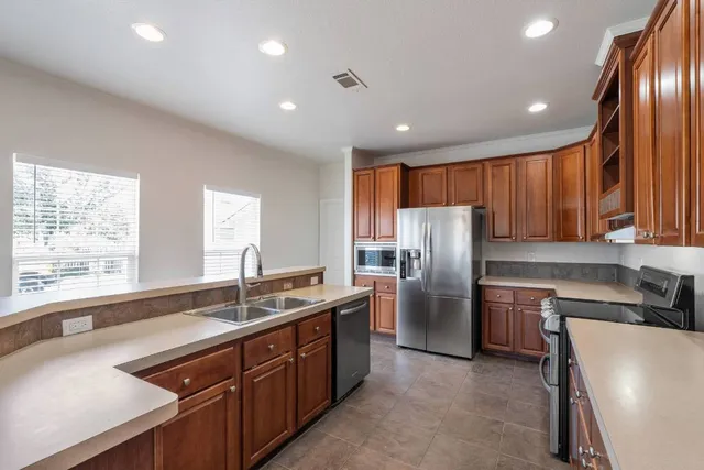a kitchen with stainless steel appliances kitchen island granite countertop a sink stove and refrigerator