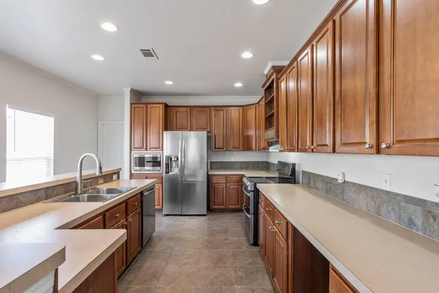 a kitchen with stainless steel appliances granite countertop refrigerator sink and wooden cabinets