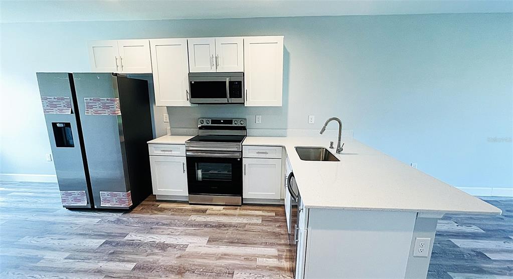 12258 Henley Avenue, Unit B Port Charlotte, FL 33981 - Photo 11 of 39 a kitchen with stainless steel appliances a stove a microwave and a refrigerator