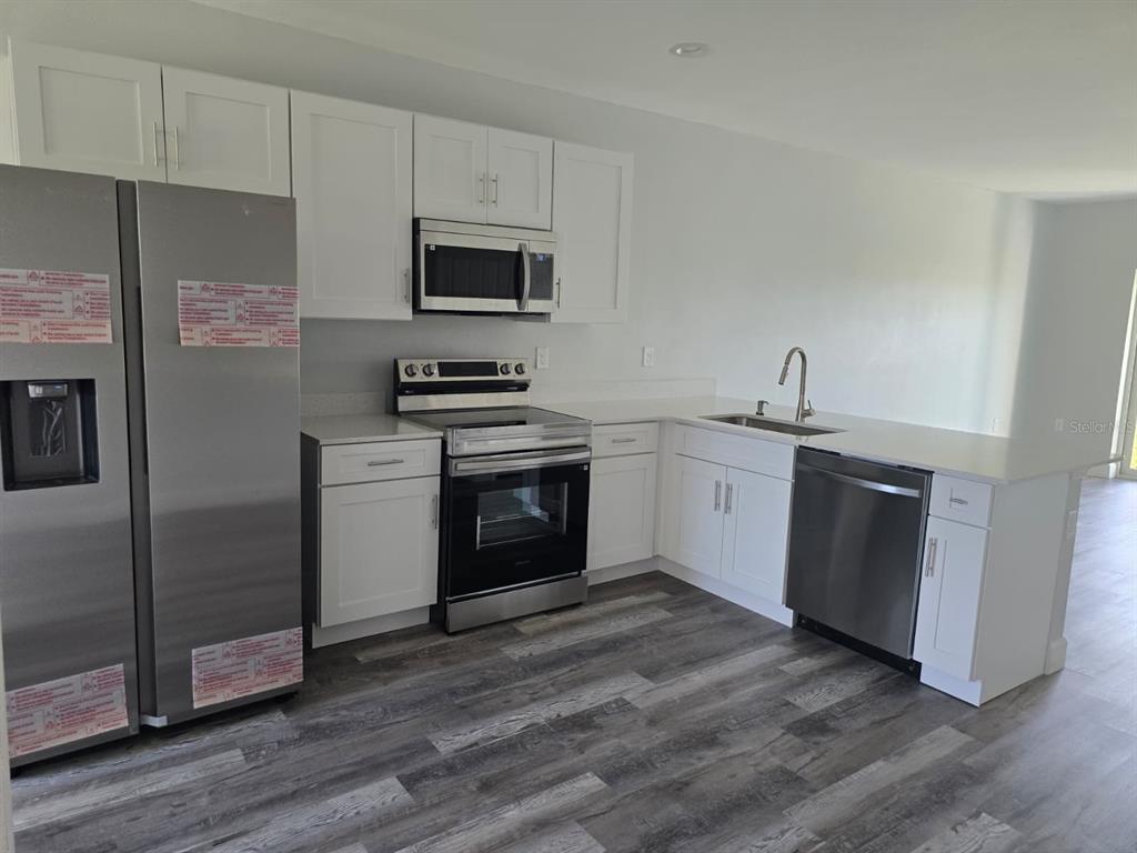 12258 Henley Avenue, Unit B Port Charlotte, FL 33981 - Photo 14 of 39 a kitchen with stainless steel appliances granite countertop a stove a sink and a microwave