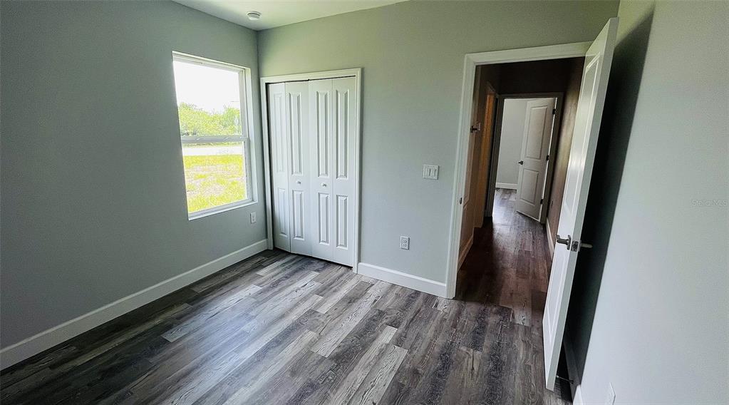 12258 Henley Avenue, Unit B Port Charlotte, FL 33981 - Photo 5 of 39 a view of an empty room with wooden floor and a window