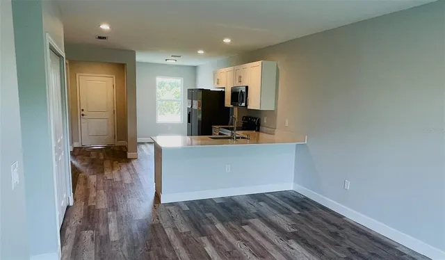 a view of a kitchen with wooden floor and a sink