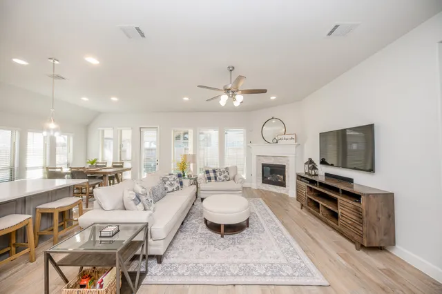 a living room with fireplace furniture a flat screen tv and kitchen view
