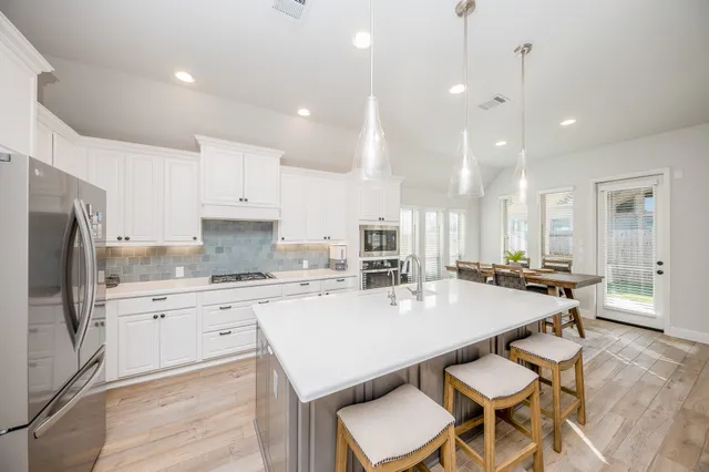 a kitchen with a sink a stove a refrigerator and chairs
