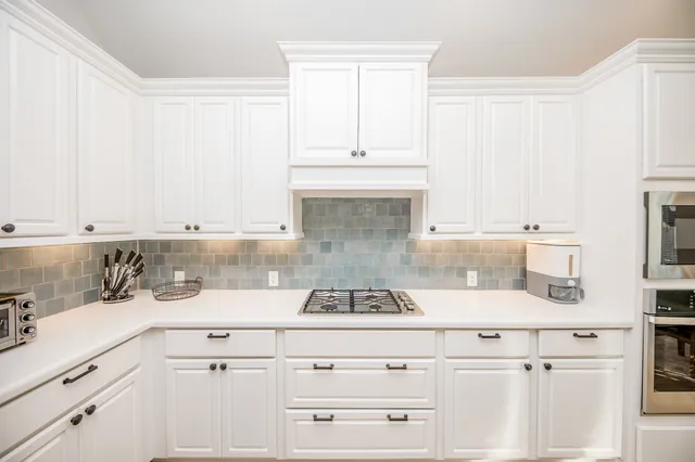 a kitchen with granite countertop white cabinets and white appliances