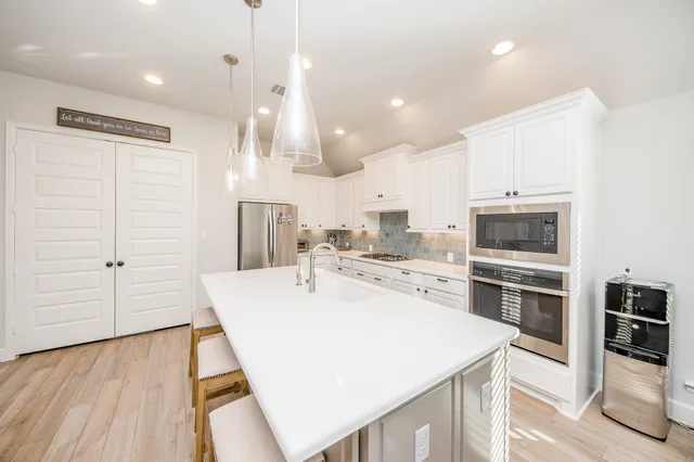 a large kitchen with kitchen island a stove a table and chairs in it