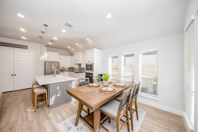a view of a dining room and livingroom with furniture wooden floor a rug and a kitchen