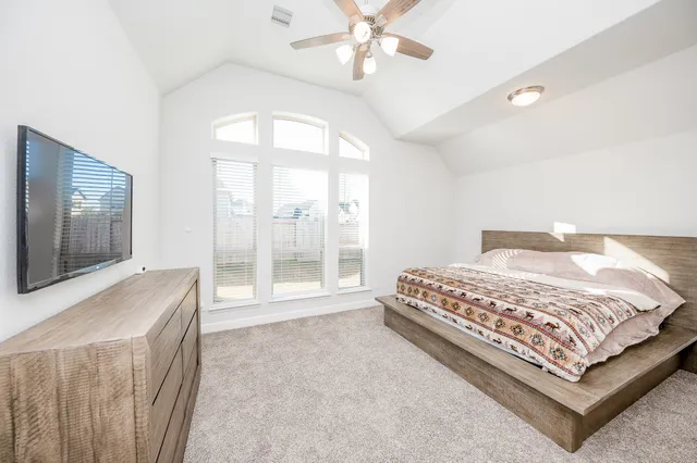 a bedroom with a large bed and a flat tv screen on dresser