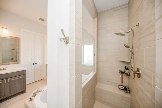 a bathroom with a tub a sink a mirror and a shower