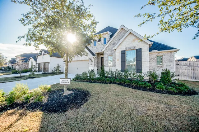 a front view of a house with a garden and lake view