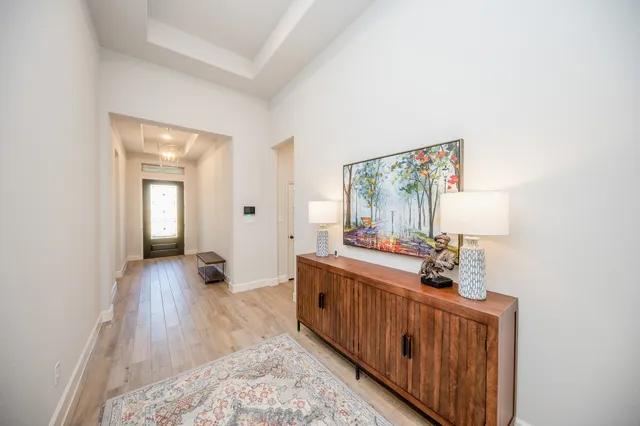 a view of a hallway to a livingroom with wooden floor and furniture