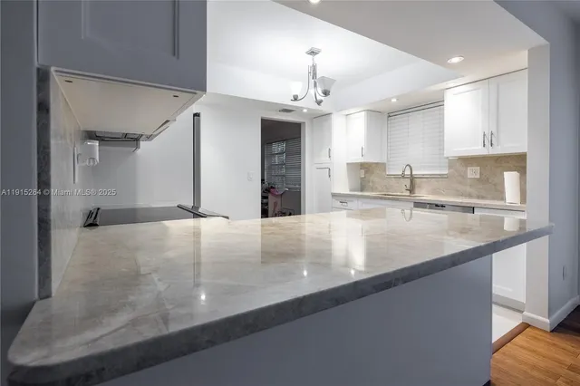 an open kitchen with granite countertop a sink a center island and stainless steel appliances