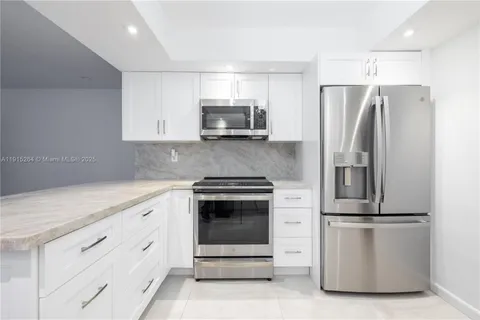 a kitchen with white cabinets and stainless steel appliances