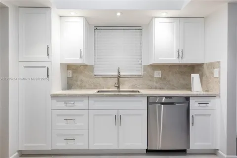 a kitchen with granite countertop white cabinets and a sink