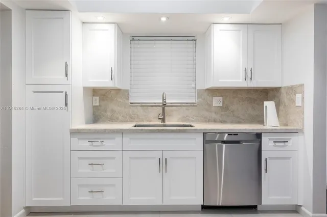 a kitchen with granite countertop white cabinets and a sink