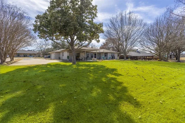 a view of a house with a yard and large trees
