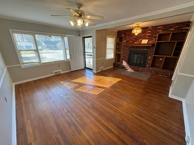 a view of a livingroom with wooden floor fireplace and window