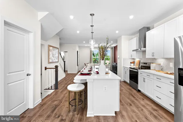 a kitchen with stainless steel appliances kitchen island granite countertop a stove a sink dishwasher and a refrigerator with wooden floor