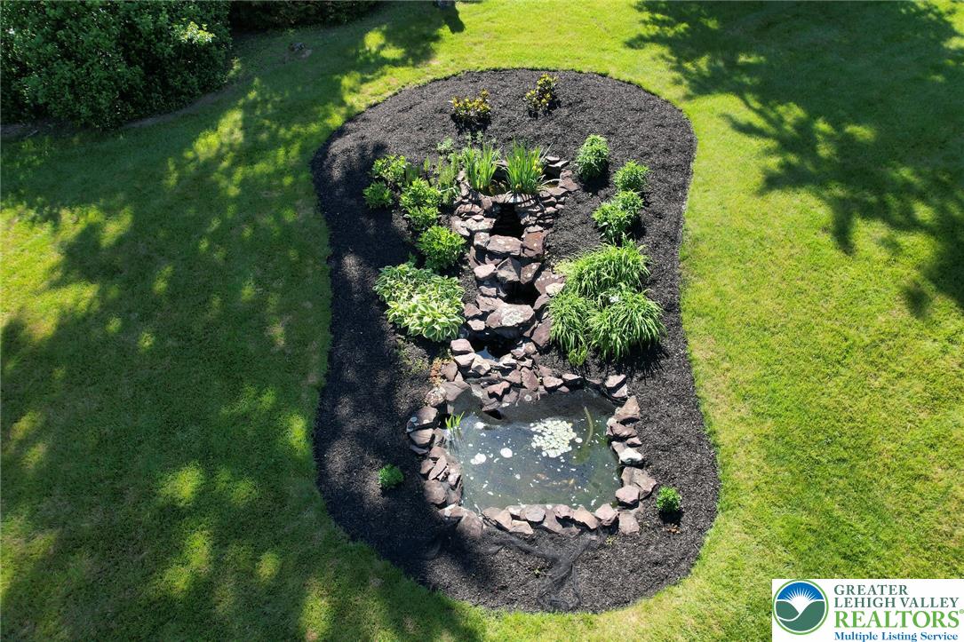 3470 Brodhead Road Bethlehem, PA 18020 - Photo 28 of 84 A tranquil water feature with a rock-lined stream and pond creates a serene garden oasis.