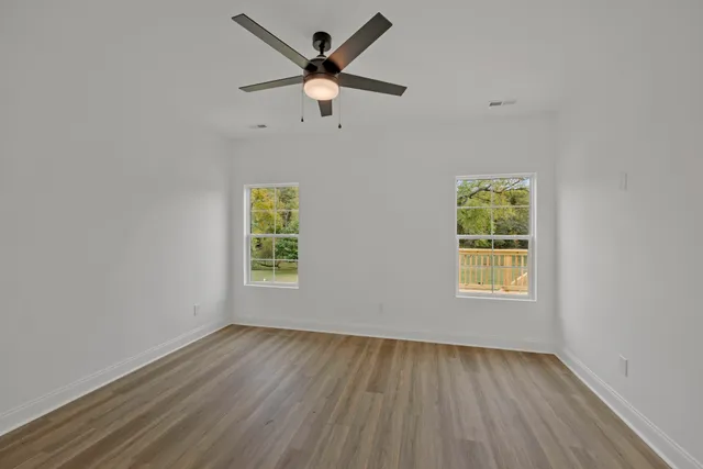 a view of a room with wooden floor and a ceiling fan