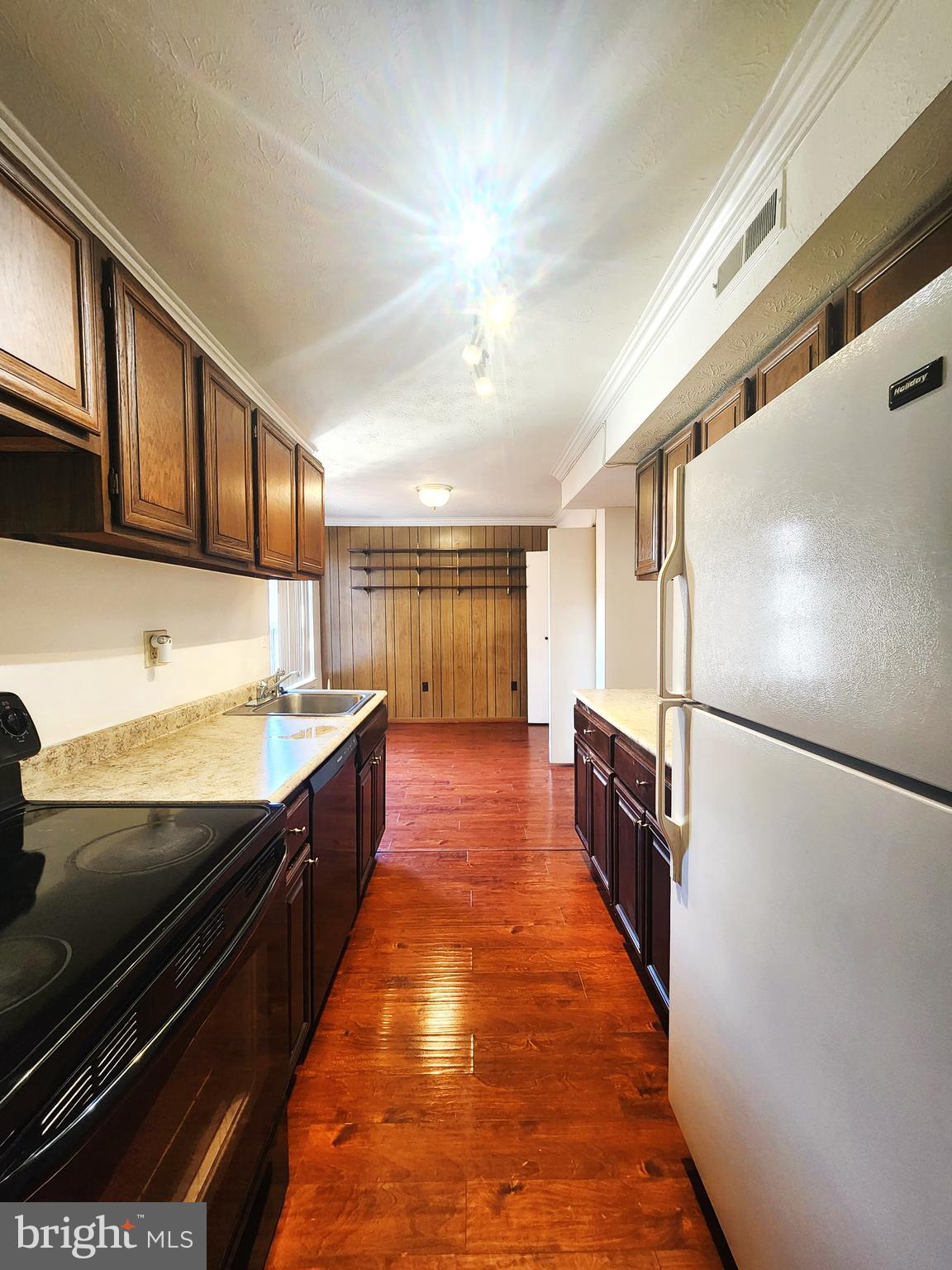 7919 Mandan Road, Unit 304 Greenbelt, MD 20770 - Photo 5 of 21 a large kitchen with stainless steel appliances a refrigerator a stove and a sink with wooden floor