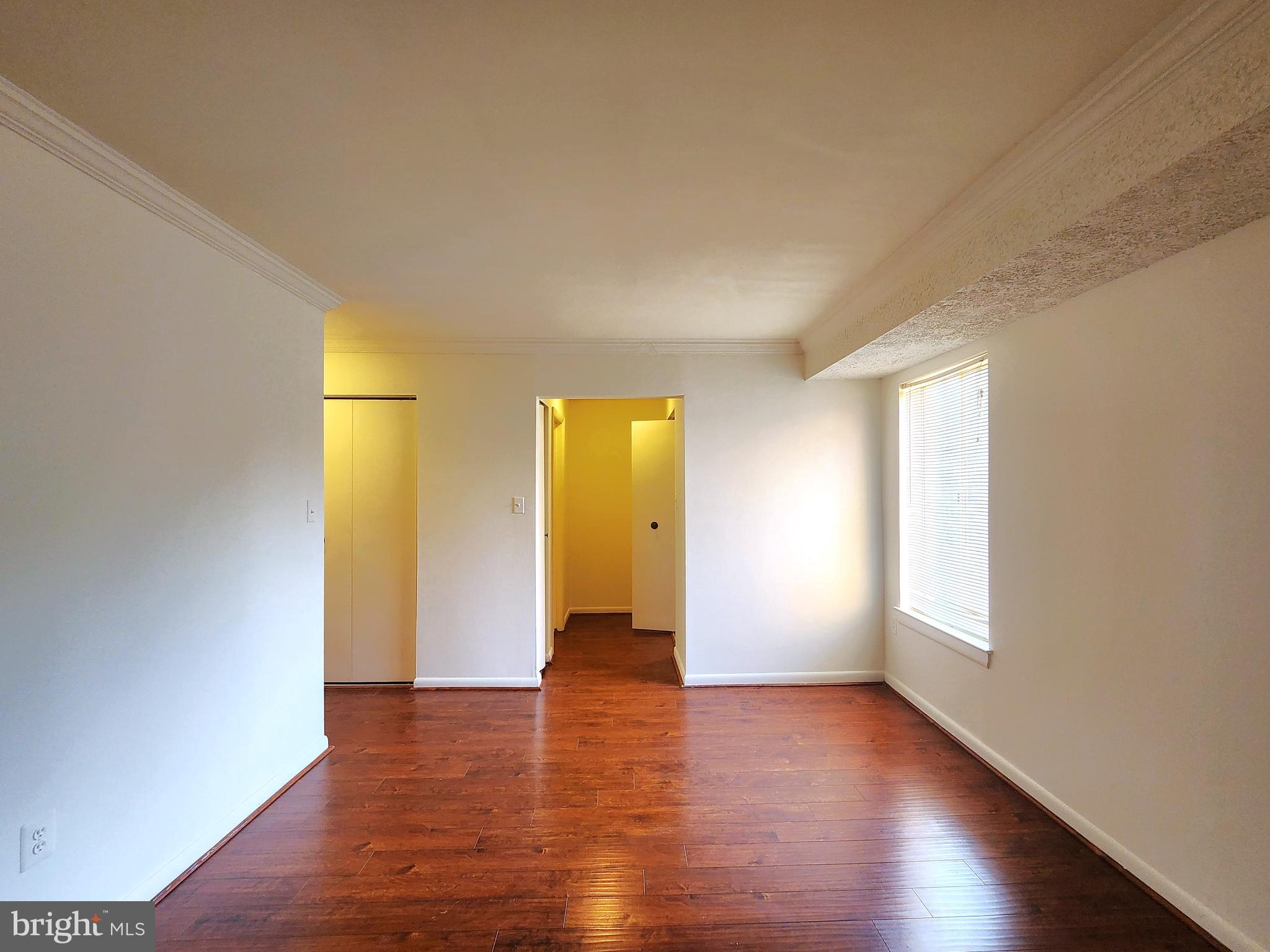 7919 Mandan Road, Unit 304 Greenbelt, MD 20770 - Photo 10 of 21 a view of an empty room with wooden floor and a window