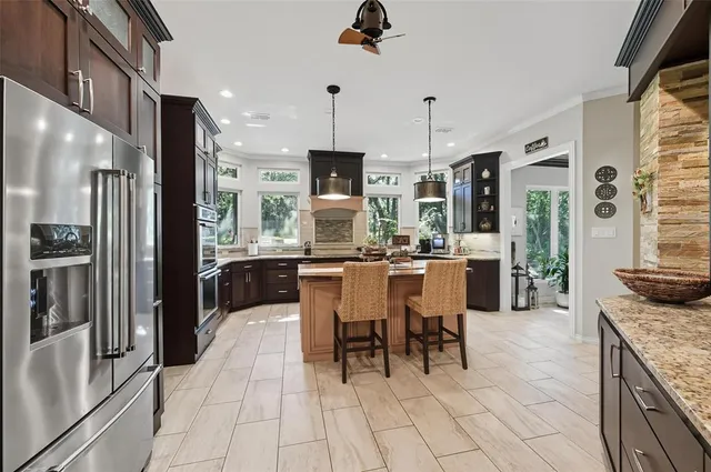 a large kitchen with granite countertop a large counter top stainless steel appliances and cabinets