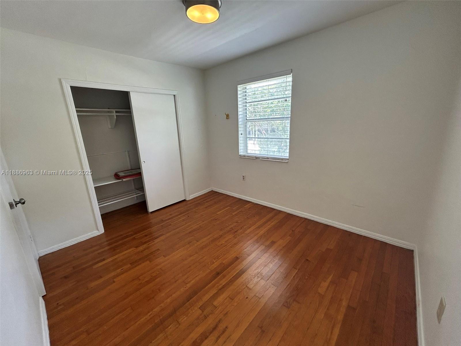 7865 Southwest 57th Avenue, Unit 47C Miami, FL 33143 - Photo 12 of 20 an empty room with wooden floor and windows