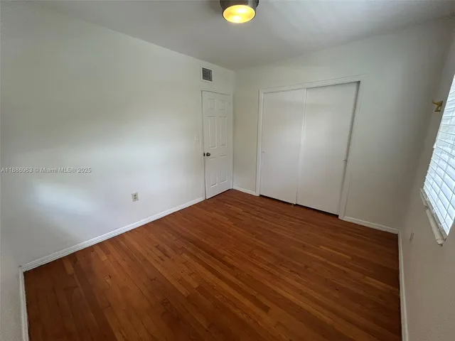 a view of empty room with window and wooden floor