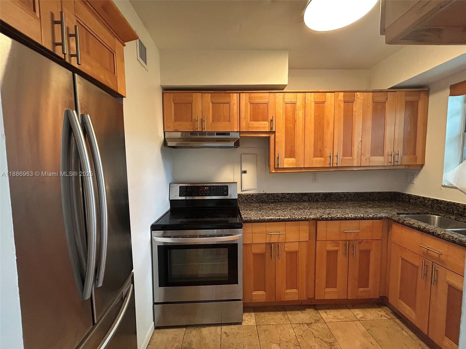7865 Southwest 57th Avenue, Unit 47C Miami, FL 33143 - Photo 6 of 20 a kitchen with stainless steel appliances wooden cabinets and a stove top oven