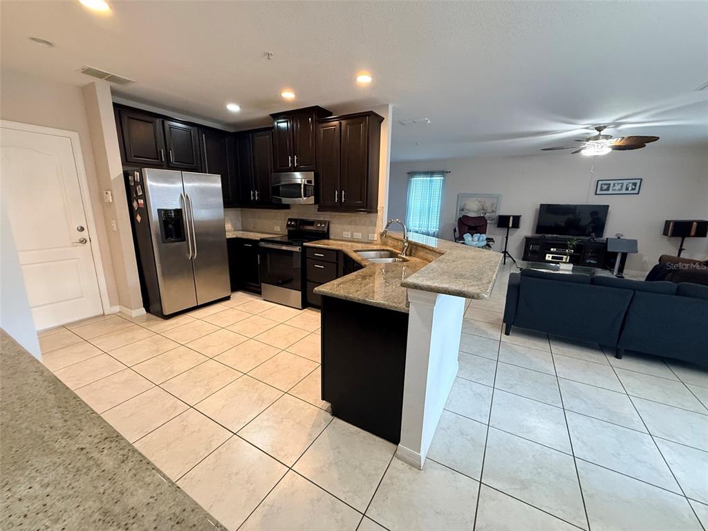 2084 Water Tupelo Way Ocoee, FL 34761 - Photo 9 of 34 a kitchen with kitchen island granite countertop a refrigerator a sink a stove top oven and cabinets