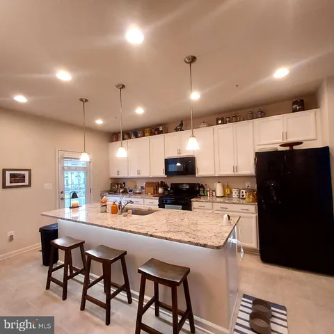 a kitchen with stainless steel appliances kitchen island granite countertop a refrigerator a sink a stove a dining table and chairs