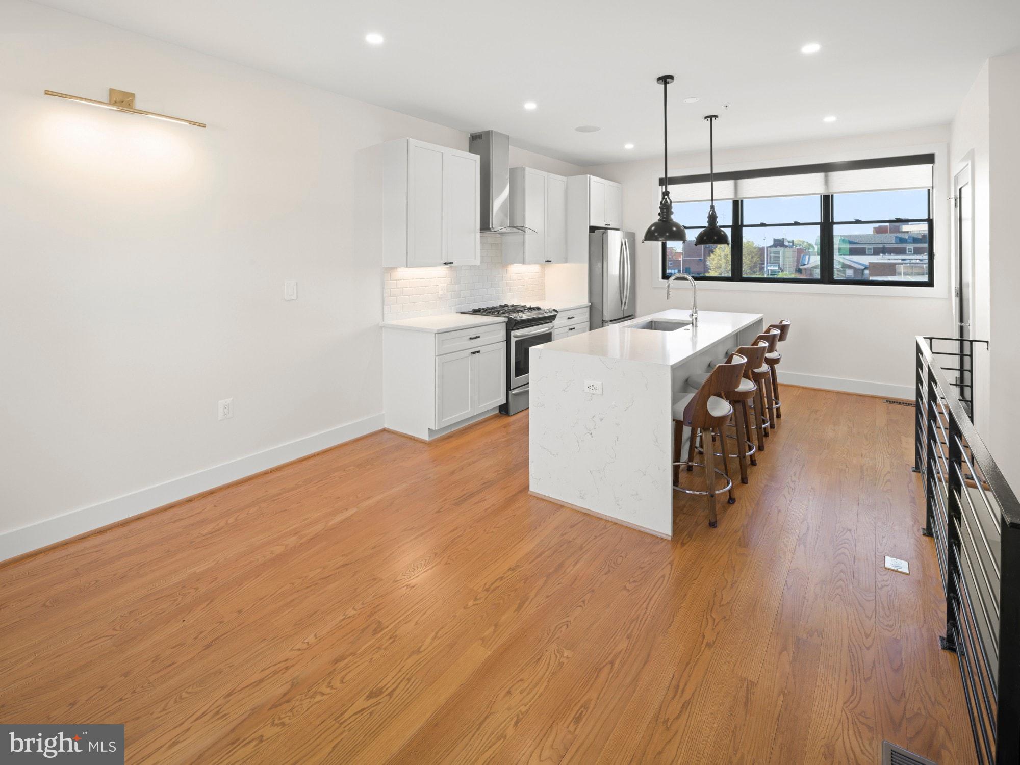 609 Gresham Place Northwest, Unit 2 Washington, DC 20001 - Photo 22 of 35 a large white kitchen with wooden floors and stainless steel appliances